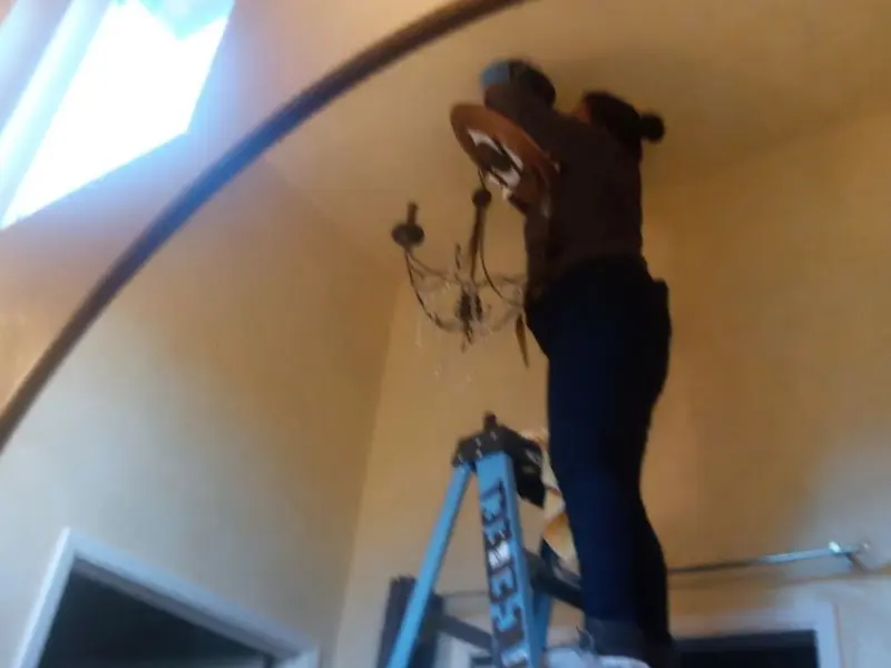 Electrician installing a chandelier in a Edwards residence
